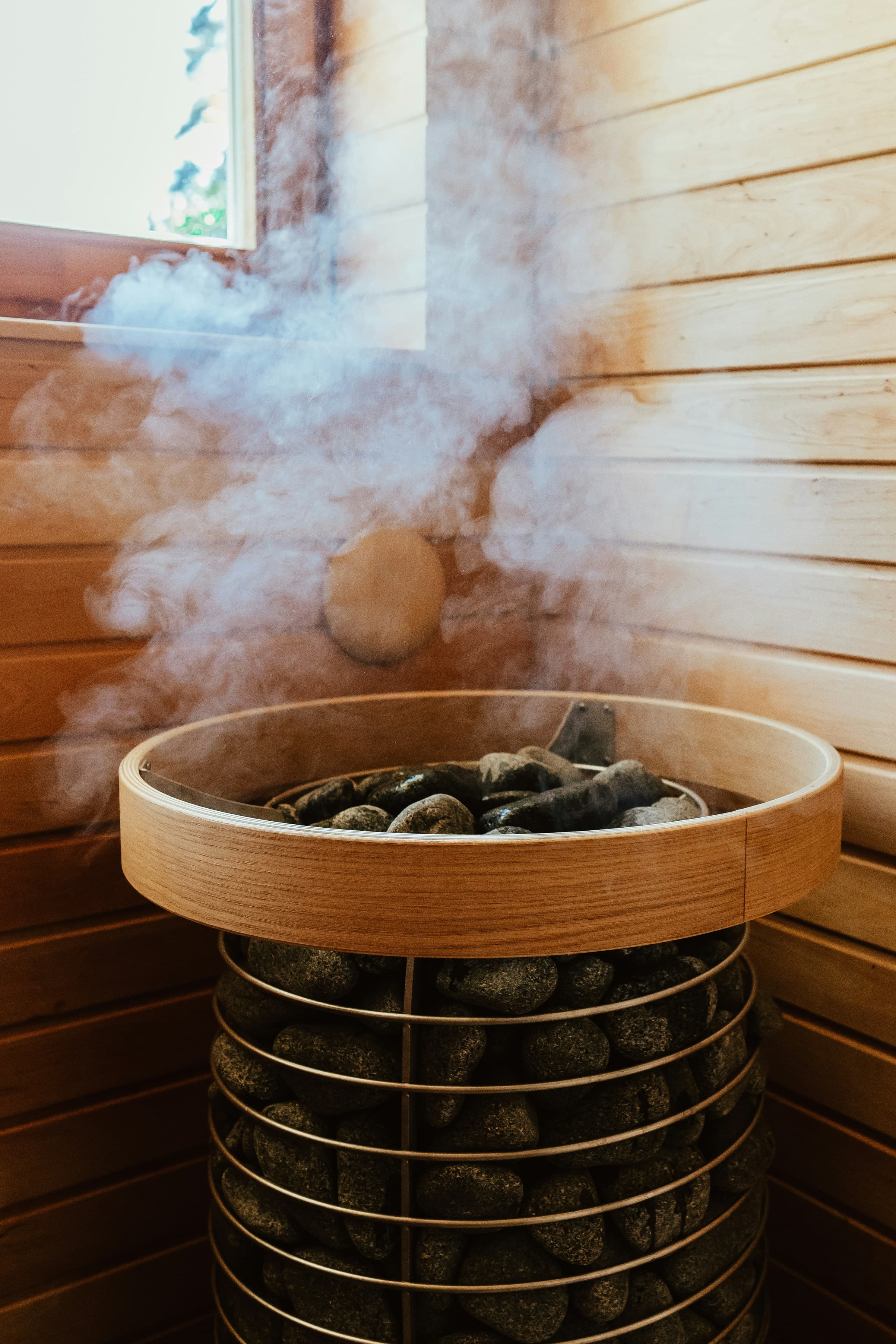 Steam rising from hot sauna stones as water is poured for löyly